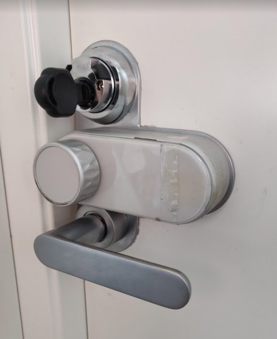 Ytterdörr med modern handtag och låscylinder med en nyckel insatt, redo att tas ut för bortalåsning.