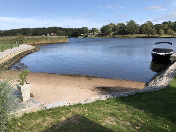 Båt vid brygga och synlig sandstrand på grund av lågt vattennivå i en insjö.