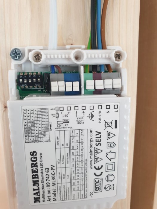 Elanslutningar och en etikett på en Malbergs dimbar LED-driver, med fråga om inkoppling i grå kontakter.