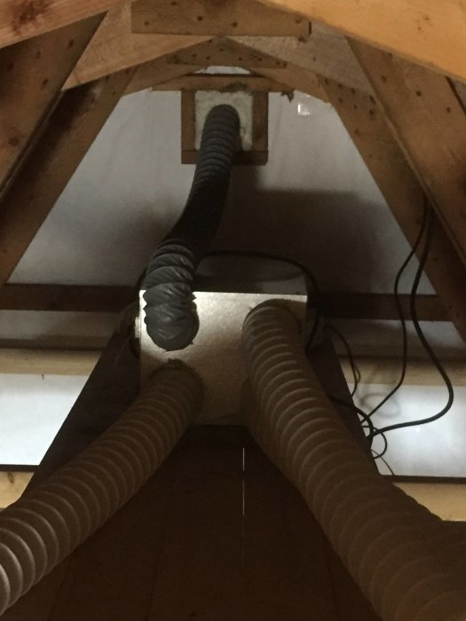 Vind med isolering och flexibla ventilationsrör på träbjälkar, tecken på renovering och uppgradering av ventilationssystem.