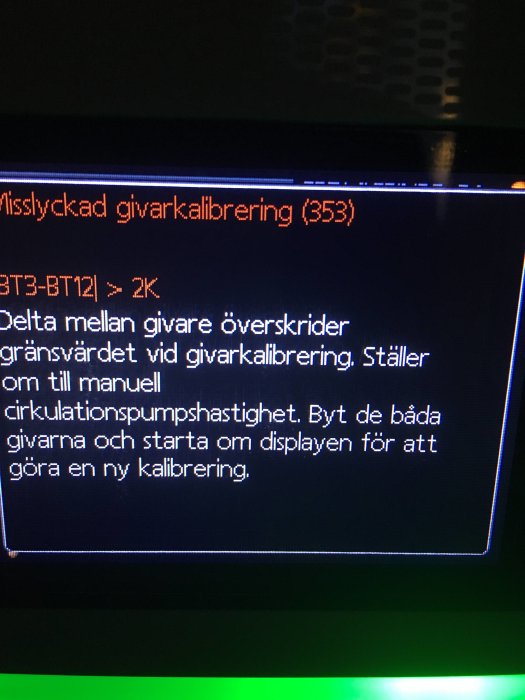 Digital display med ett felmeddelande om misslyckad givarkalibrering från en värmepumpsstyrning.