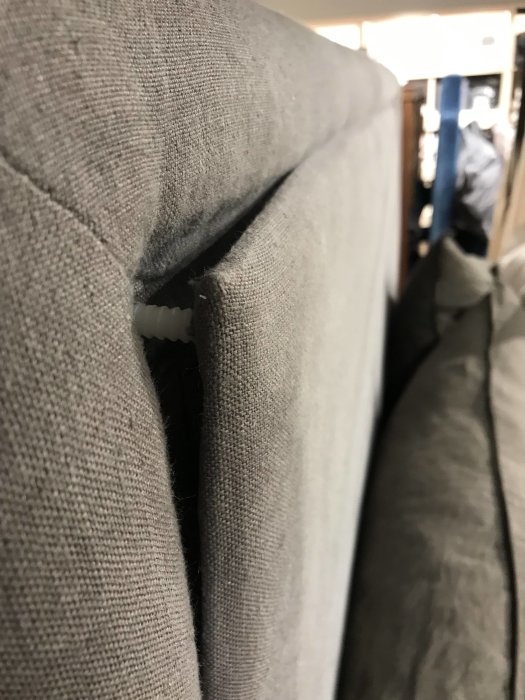 Närbild på kanten av en grå tygsänggavel utan nitar.