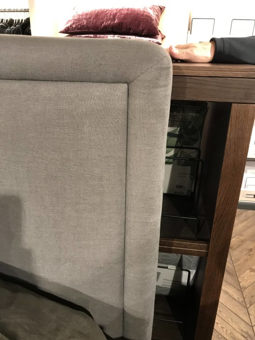 Grå tygklädd sänggavel med ren kant utan nitar, närbild på textur och design.