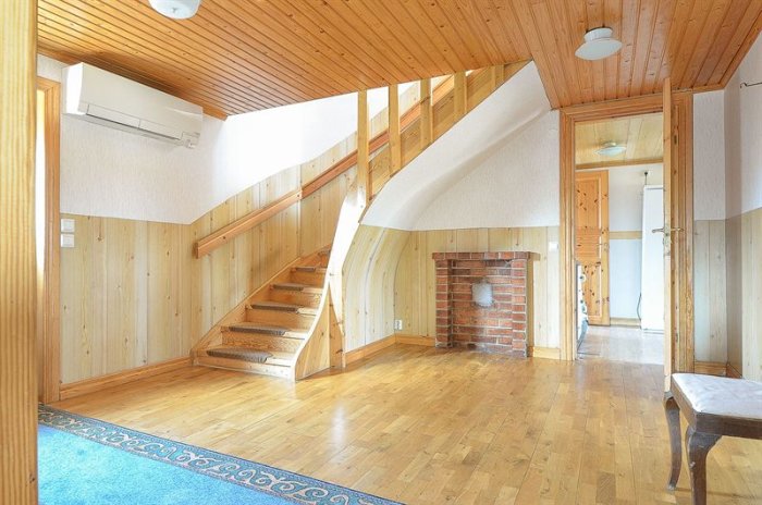Interiör av hus med trätrappa, luftkonditionering och bricked panna.