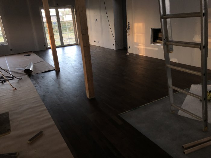 Nyinstallerad parkettgolv i ett rum under renovering med synliga byggmaterial och verktyg.