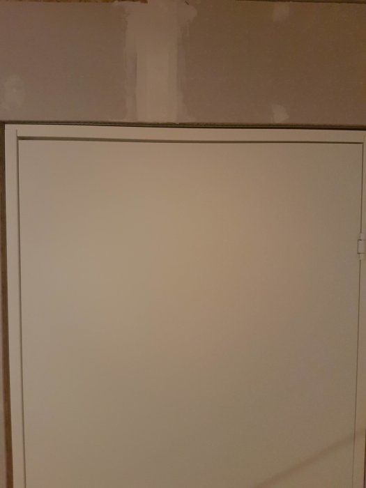 Nymonterad innerdörr med synlig glipa i övre och nedre hörn samt nära nedre gångjärn.