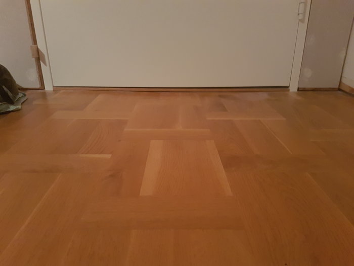 Vita innerdörrar med synlig glipa högst upp och nederst i hörnen på ett trägolv.