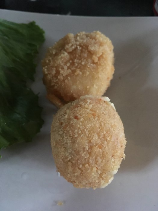 Hemgjorda chilicheese-bollar panerade och friterade, serverade på ett vitt fat med salladsblad.
