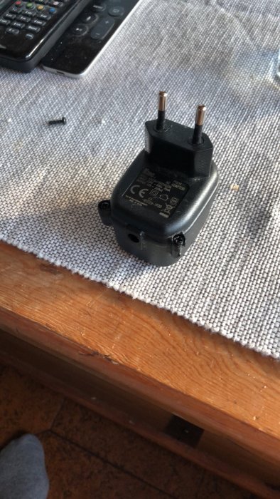 Defekt nätadapter på bord, specifikationer synliga, söker ersättare.