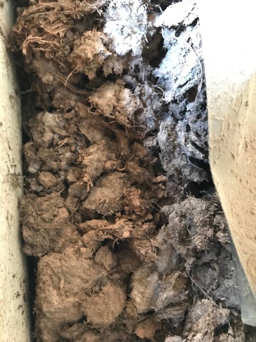 Brun isoleringsmaterial upptäckt bakom inbyggd skåp i hus från tidigt 1900-tal.