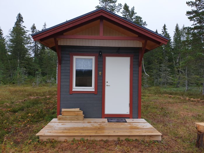 En liten stuga med träveranda i en skogsglänta, potentiell plats för solceller eller elverk.