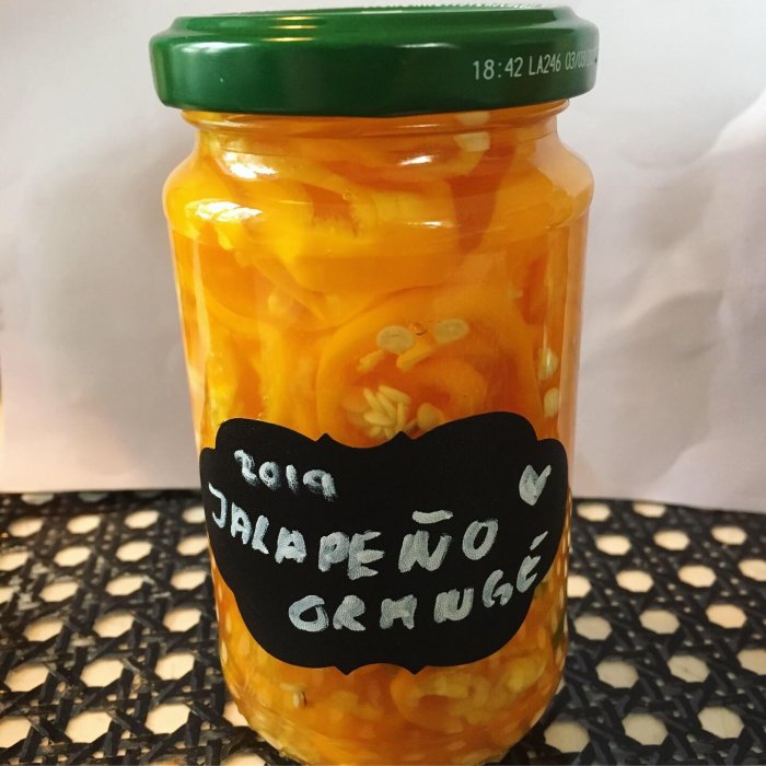 Inlagda gula jalapeños i en glasburk med svart etikett "2019 Jalapeño Gruuuge