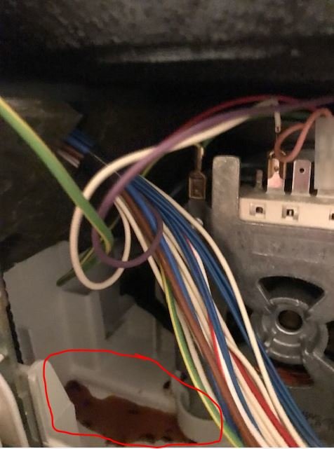 Inre del av maskin med färgglada kablar och komponenter, samt rostfärgat dropp markerat i rött.