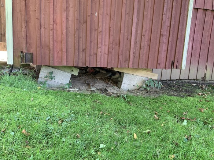 Gammal byggbod på hjul med snedställd stålram och ojämn grundning syns under trädäck.