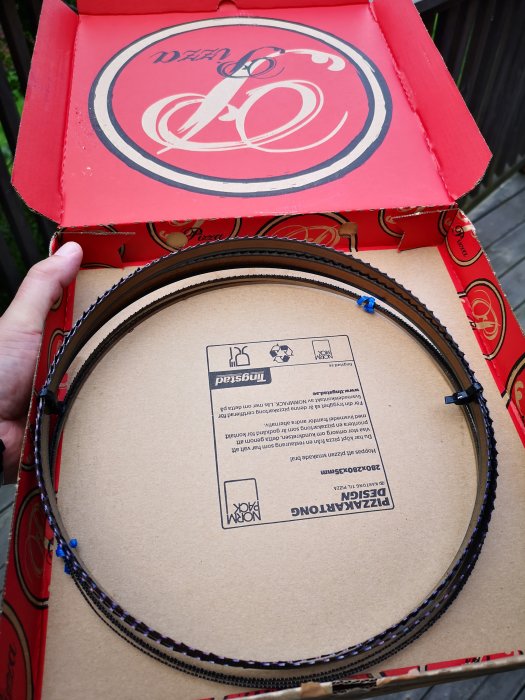 Bandsågsblad förpackade i en öppen pizzakartong som visar bladen och leveransinformation.