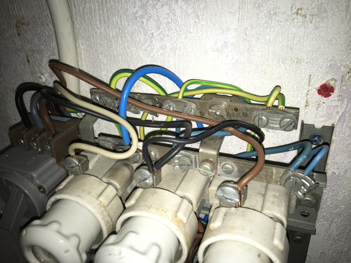 Elektriska kablar och säkringar i ett proppskåp där en dold nolla är synlig bakom andra kablar.