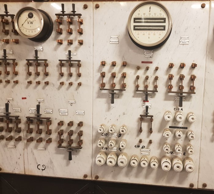 Kontrollpanel med mätare, knivbrytare och väljare för en äldre motorgenerator.