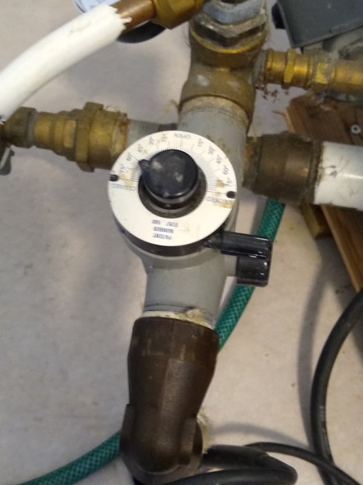 Vatteninstallation med Wellmate HP 110 luftinjektor och vred med pil, samt svart spak på en rörkoppling.