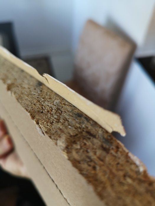 Træliste fastgjort på kanten af en træplade, med fokus på en løs list, anvendt som kant for indpasning i et rum.