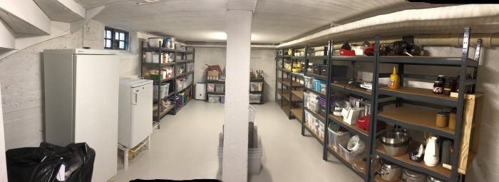Panoramavy över ett ordnat förrådsrum med hyllor fyllda med förvaringslådor och hushållsartiklar.