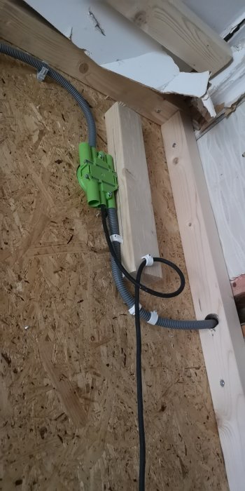 Elektrisk dosa fäst på en trästomme, med kablar i flexibla rör vid en OSB-skiva.