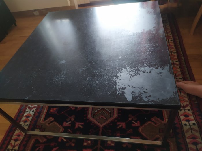 Soffbord med skifferskiva och synliga fläckar från rött vin, behöver renovering.