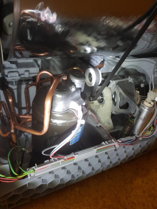 Interiör av en torktumlare med synliga elektriska komponenter och kablar.