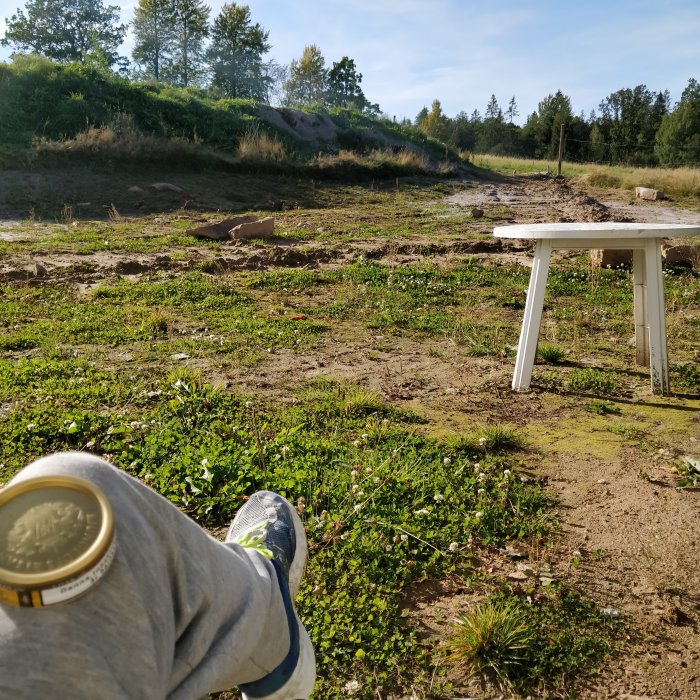 Person som tar en paus utomhus med vy över ett tomt landskap med ett vitt bord i förgrunden.