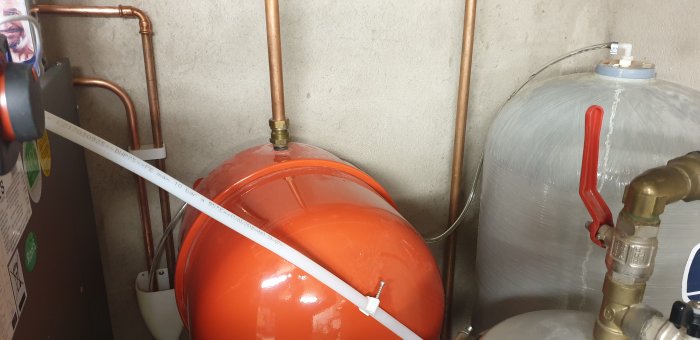 Installation av PVC-slang ansluten till orange expansionskärl i ett värmesystem.