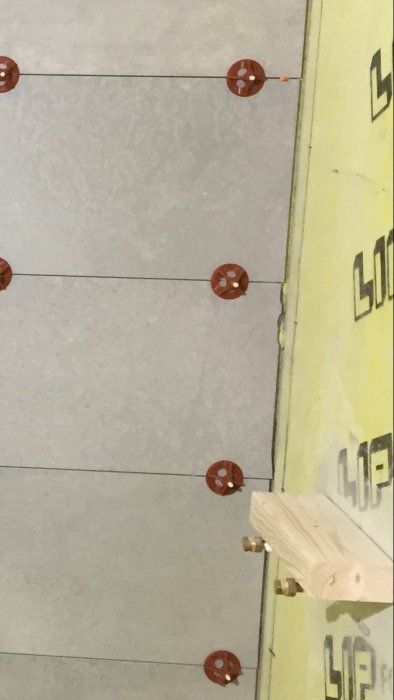 Kakelvägg under installation med hel plattor till vänster och ojämnt kapat kakel till höger.
