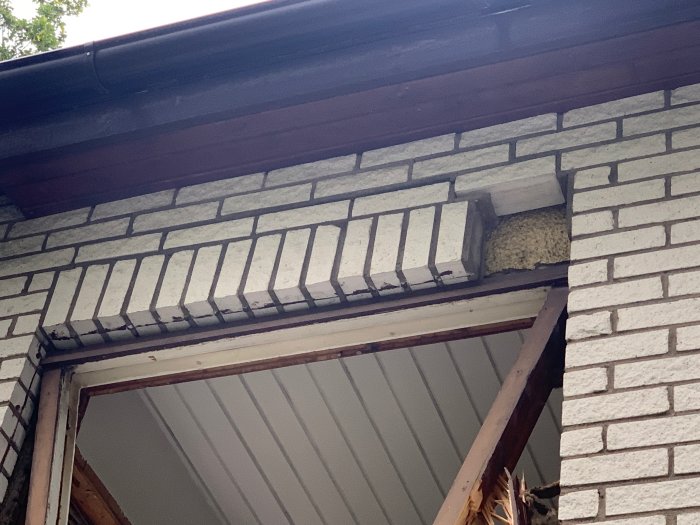 Schade aan tegelfaçade boven venster na verwijdering, met zichtbare luchtspouw en isolatie.