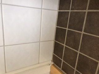 Kaklat badrum med linjerade fogar mellan golv- och väggkakel, bilden är roterad.