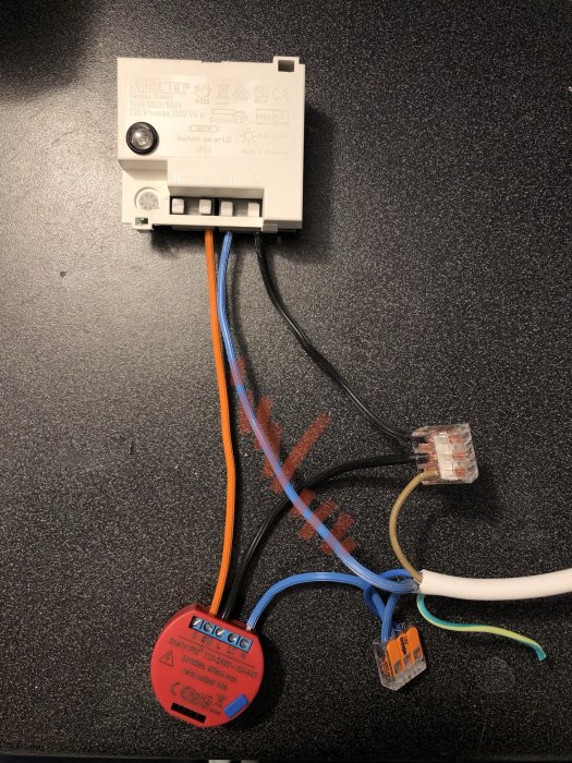 Elkomponent med anslutna kablar och WAGO-klämmor på en mörk yta, visar hur man kopplar en givare till en Shelly-enhet.