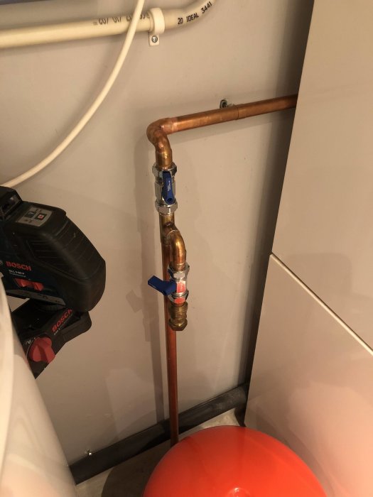 Kopparledning med kranar för att kontrollmäta och byta tryck i kärlet, monterat i ett hörn.