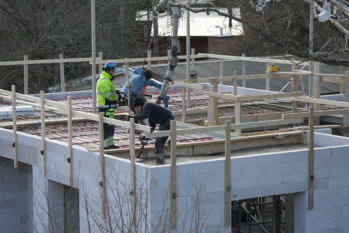 Arbetare utför betonggjutning i balkformar på en byggarbetsplats.