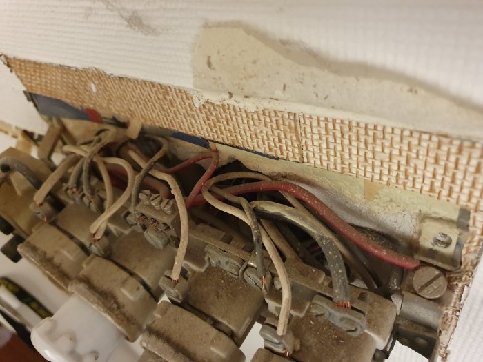Gammal säkringslåda med synliga ledningar och föråldrade komponenter i ett renoveringsbehovigt skick.