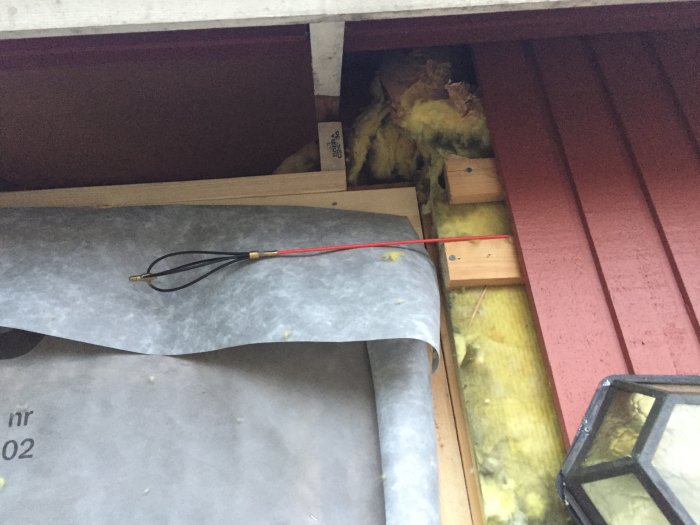 Kabel dragen genom tak med isolering och rotdosa synlig.