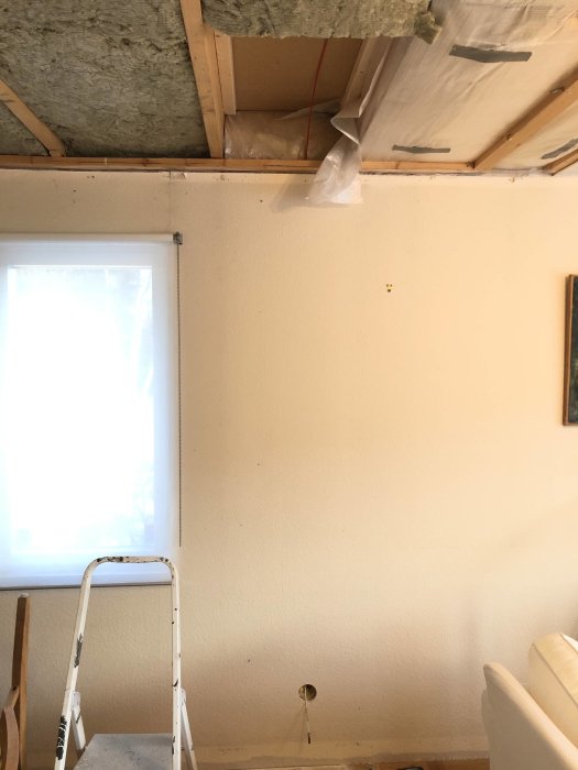 Installation av rotdosa i vägg med synligt hål och kabel, samt öppet tak med isolering.