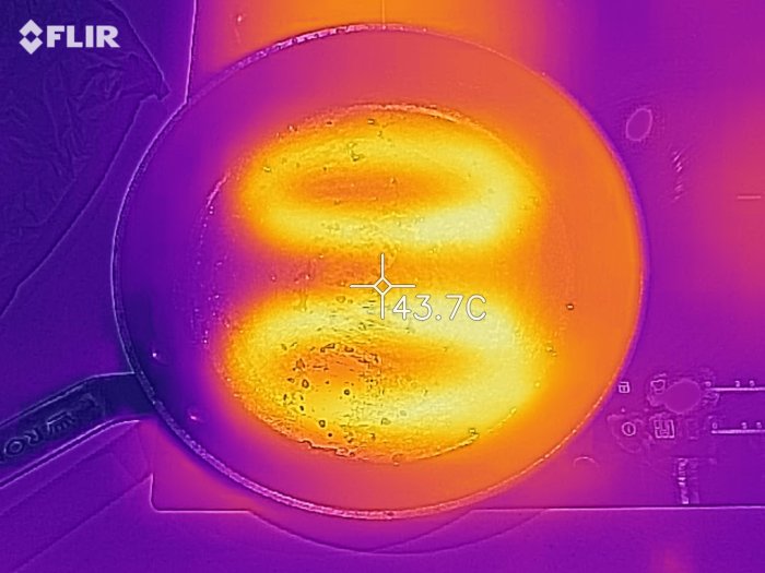 Termisk bild av gjutjärnspanna på induktionshäll med temperaturvisning 43.7°C.