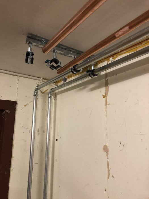 Nya kopparrör och värmerör installerade längs en vägg för att ersätta gamla, rostiga rör.