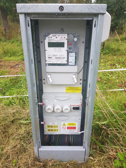 Elektricitetsmätare och säkringsskåp för solcellsanläggning med skyltning och försörjningskablar.