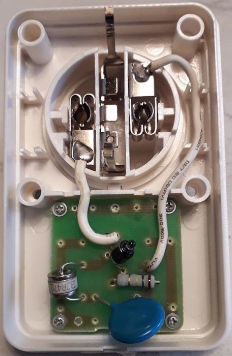 Insidan av en vägguttag med synliga komponenter som kopplingsklämmor, elkablar och kretskort.