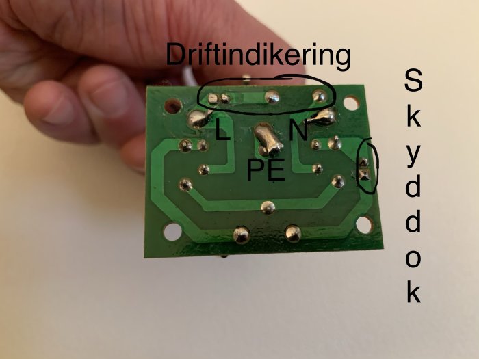 Portabelt överspänningsskyddets kretskort med markerade anslutningar för jord, fas, nolla och skydd OK.
