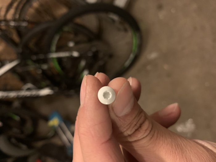 Närbild på en hand som håller en vit plastbricka med en cykel i bakgrunden.