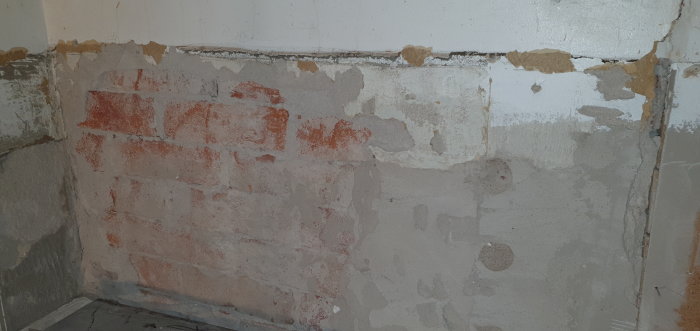 Renoveringsarbete på köksvägg med borttaget kakel och ojämnt murbruk.