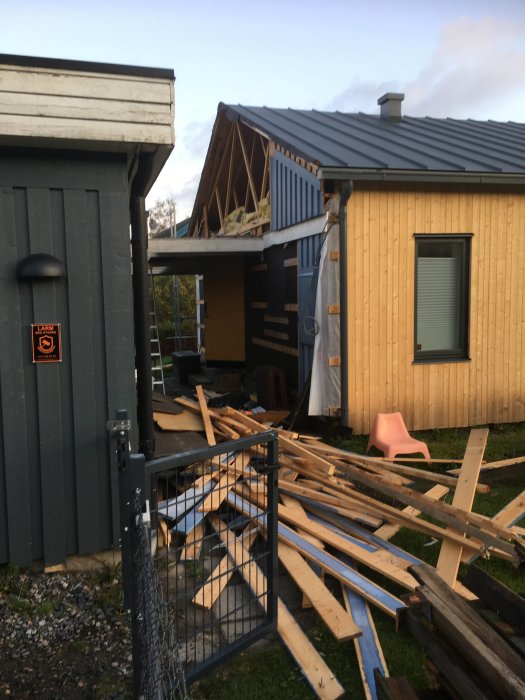 Hus under renovering med borttagen panel och upptaget byggavfall på marken.