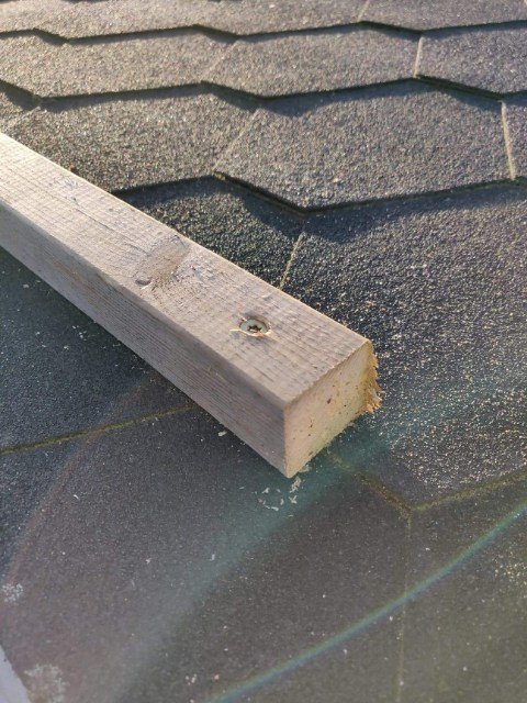 Träregel fäst vid takpapp med synliga skruvhål, tecken på dåligt hantverk.