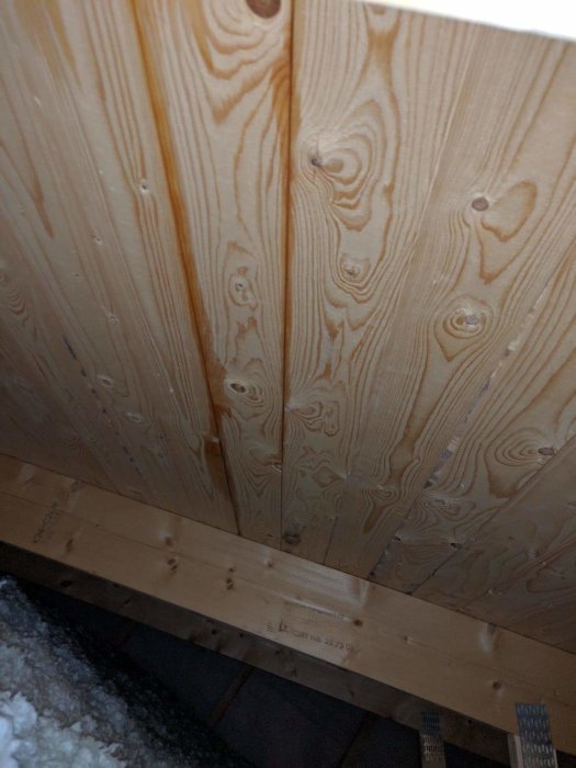 Vattenskador på träbjälkar och innertak efter läckage, med tydliga fuktmärken.