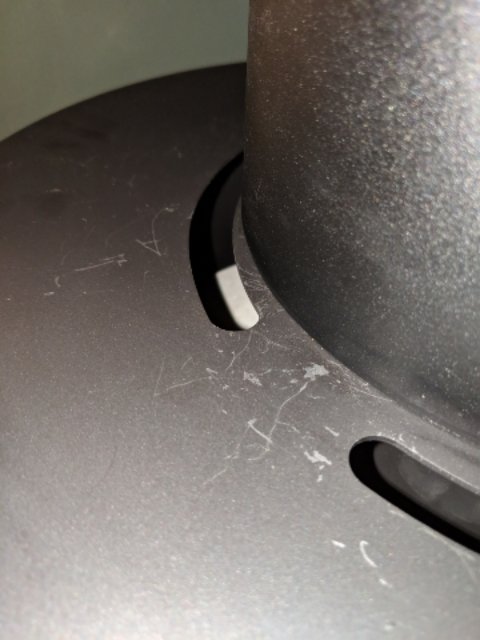 Närbild på en svart kamin med repor på ytan, vilket tyder på skadad lackering.