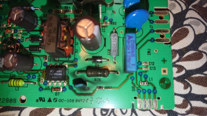 Bränt elektroniskt komponent och skador på ett grönt kretskort.